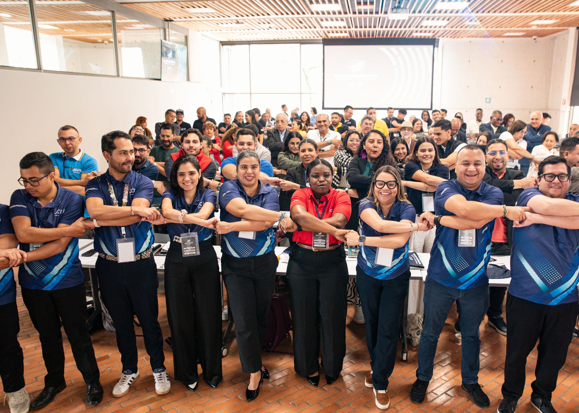 Miembros de JCI Colombia con los brazos entrelazados durante un encuentro nacional